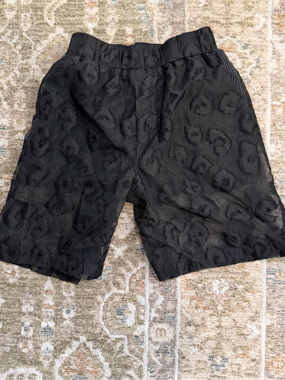 Vladimir Karaleev textured black shorts with tonal abstract pattern.